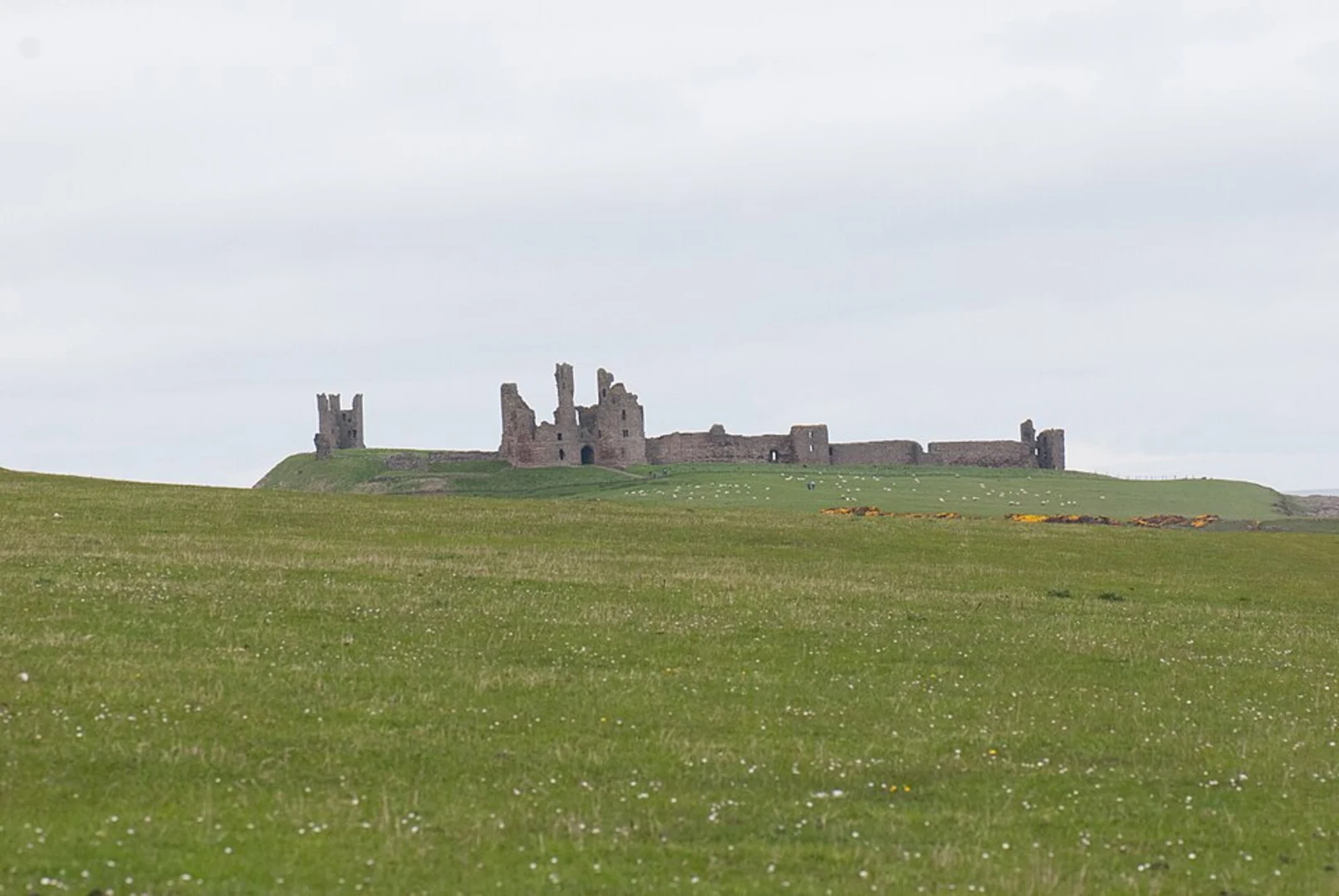 An image depicting the trail Dunstanburgh Castle via England Coast Path and its surrounding area.